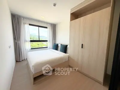Modern bedroom with large window and stylish wardrobe in a bright apartment.