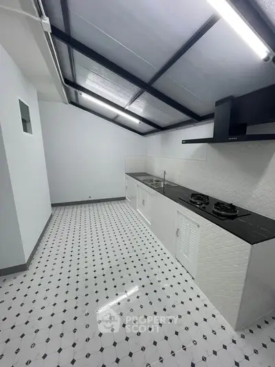 Modern kitchen with sleek gas stove and stylish black and white tile flooring.