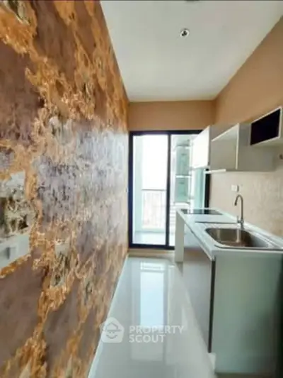 Modern kitchen with sleek design and unique wall texture, featuring stainless steel sink and ample natural light.
