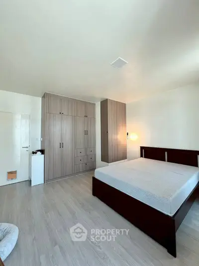 Spacious bedroom with modern wooden wardrobe and sleek flooring