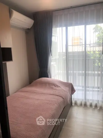 Cozy bedroom with large window and modern air conditioning unit, perfect for natural light lovers.
