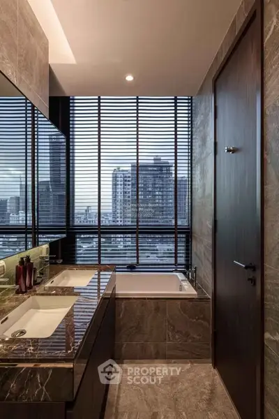 Luxurious bathroom with city view, featuring dual sinks and a modern bathtub.
