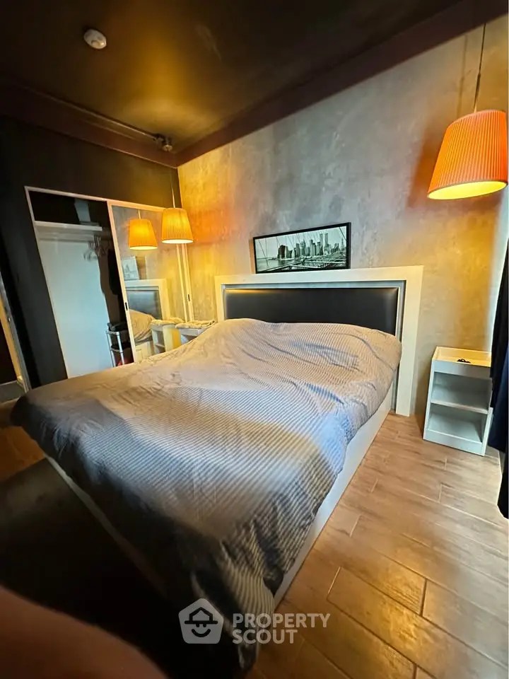 Modern bedroom with stylish lighting and wooden flooring, featuring a cozy bed and mirrored wardrobe.