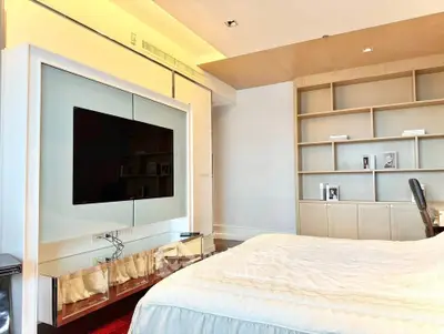 Luxurious bedroom with modern TV setup and elegant shelving, perfect for relaxation and entertainment.