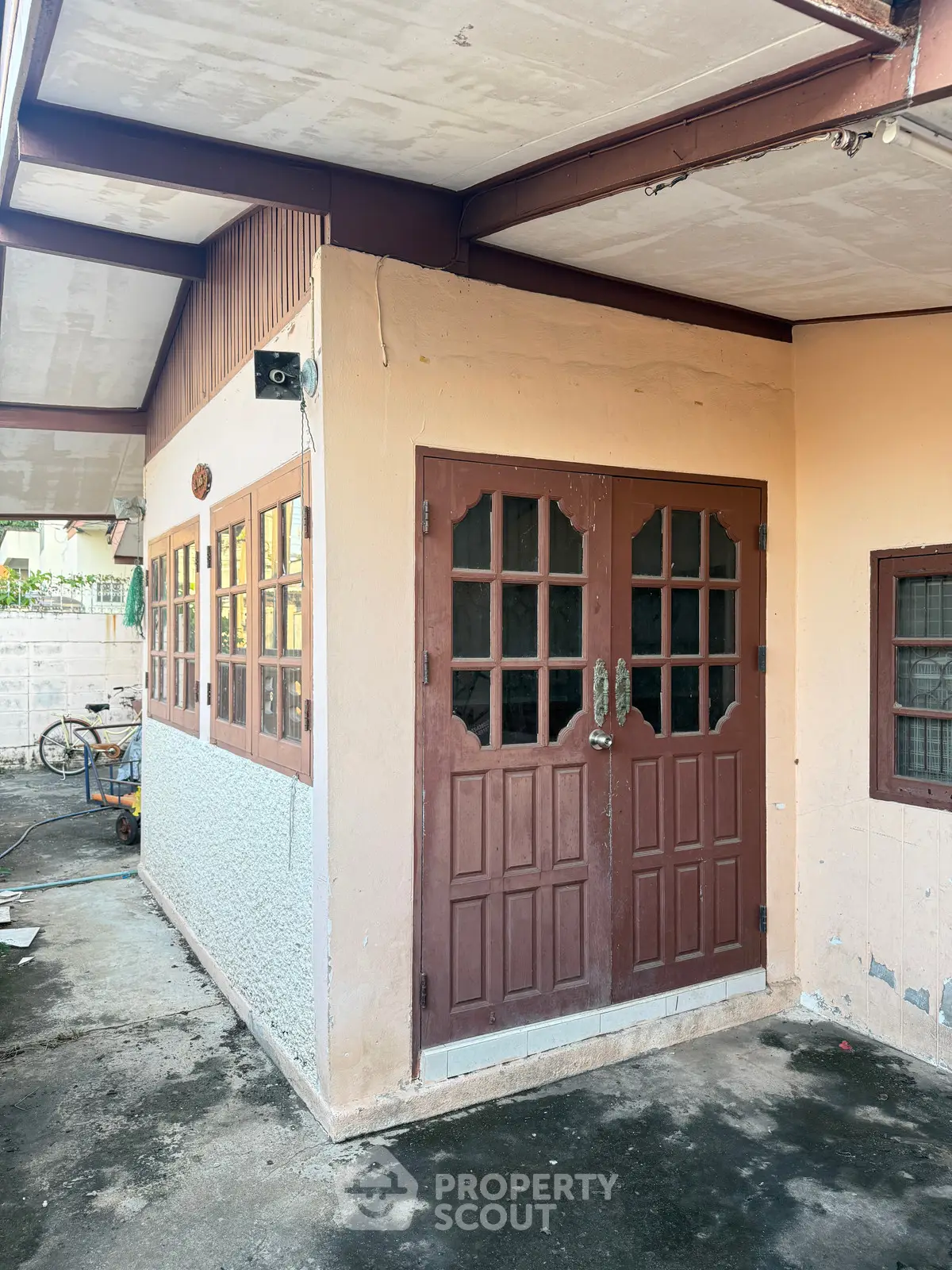 Charming rustic exterior with wooden doors and covered patio, perfect for cozy outdoor living.