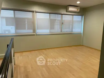 Spacious empty room with large windows and wooden flooring, perfect for customization.