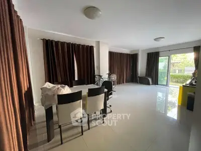 Spacious modern living room with dining area and large windows offering garden views.