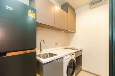 Modern compact kitchen with appliances including fridge and washing machine, sleek cabinetry, and minimalist design.