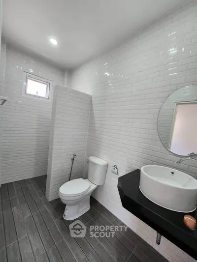 Modern bathroom with sleek design, featuring white subway tiles and a round mirror.