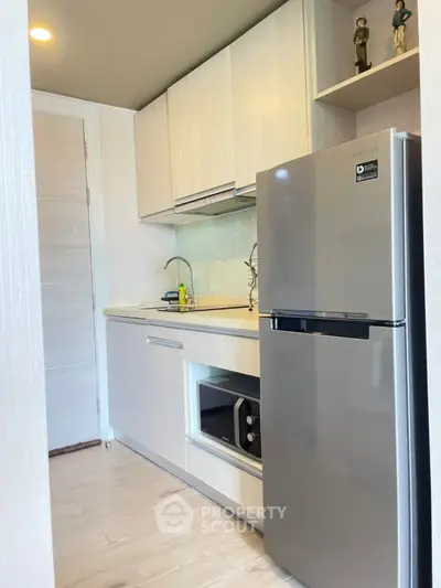 Modern kitchen with sleek cabinets and stainless steel fridge in a compact layout.