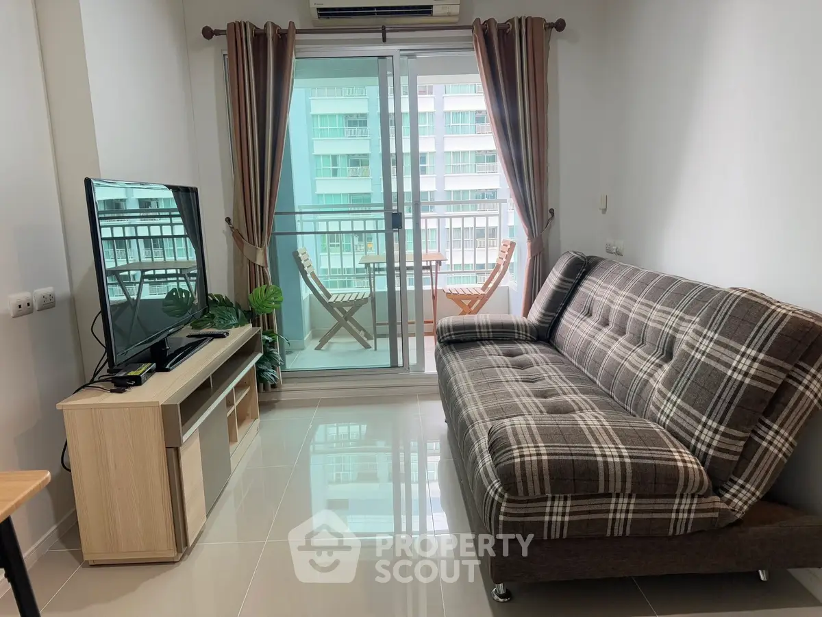 Modern living room with balcony view, featuring stylish sofa and entertainment center.