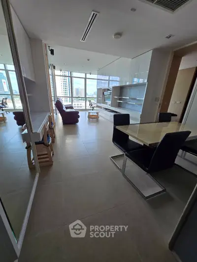 Spacious modern living room with city view, featuring sleek furniture and ample natural light.