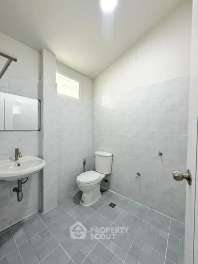 Spacious bathroom with modern fixtures and tiled walls in a bright real estate property.