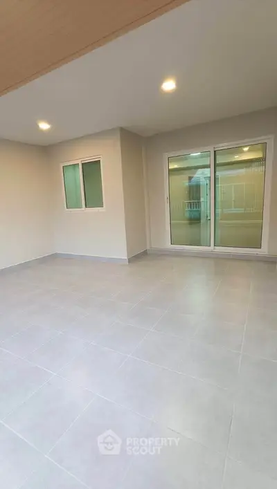 Spacious tiled balcony with sliding glass doors and modern lighting