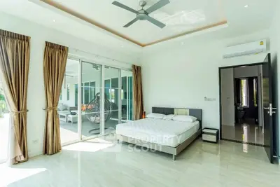Spacious bedroom with modern design and large windows opening to a balcony.