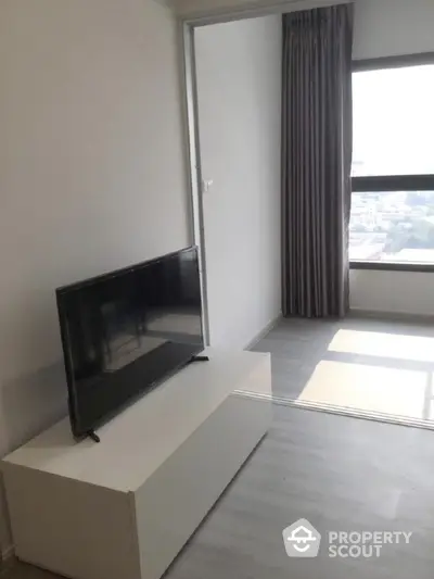 Modern living room with sleek TV stand and large window offering city view