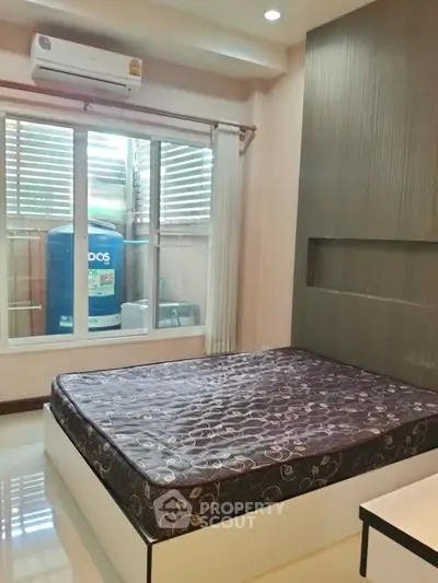 Modern bedroom with large window and air conditioning unit, featuring a comfortable mattress and sleek design.