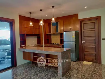Modern kitchen with granite countertops and wooden cabinets, featuring open layout and stainless steel appliances.