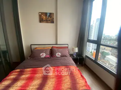 Cozy bedroom with city view, featuring modern decor and large windows for natural light.