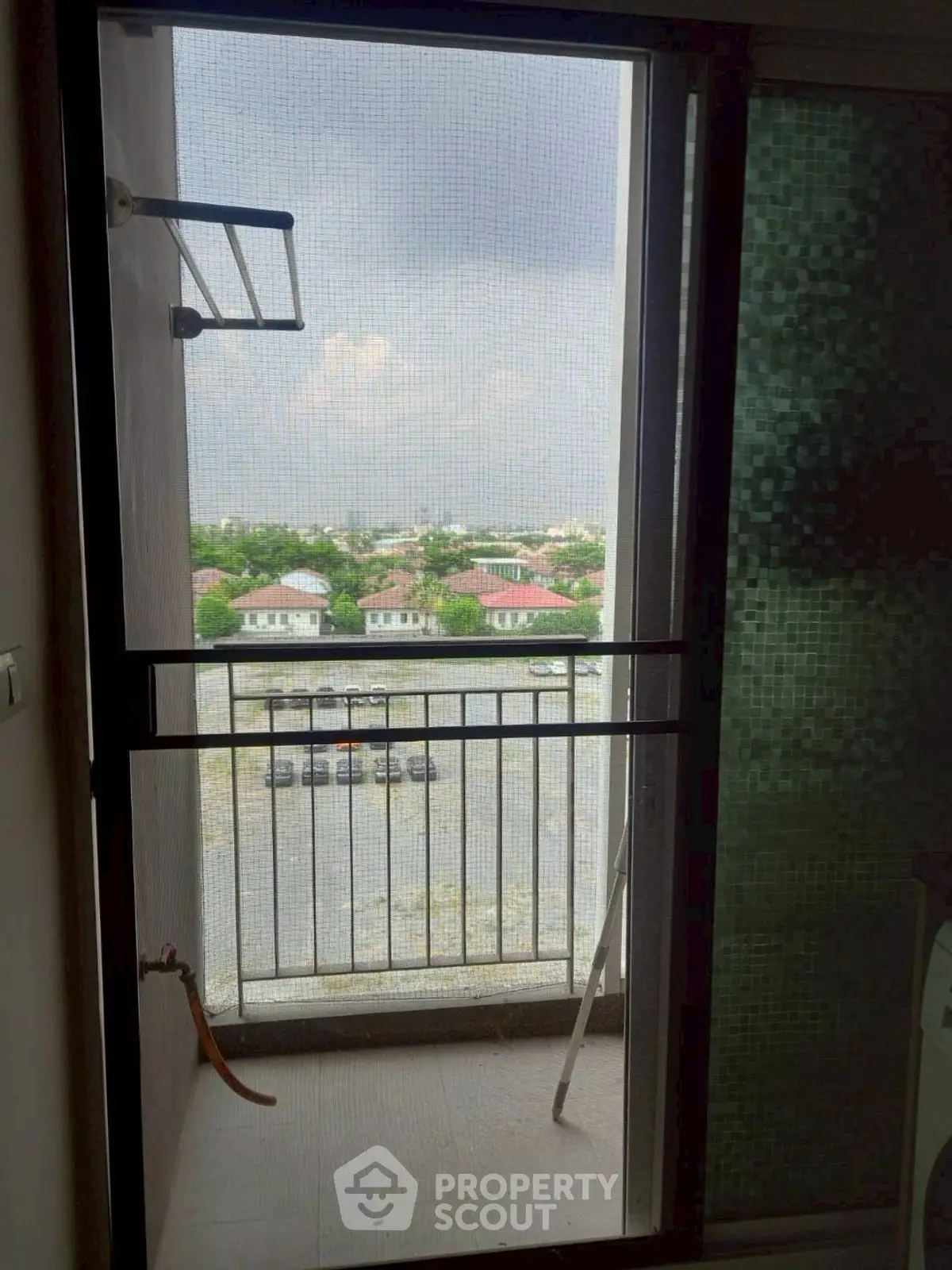 Cozy balcony with scenic view of residential area and cloudy sky.