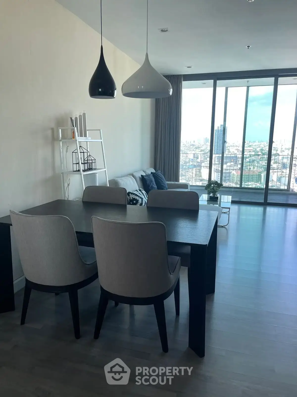 Modern dining area with city view and stylish lighting in a high-rise apartment.