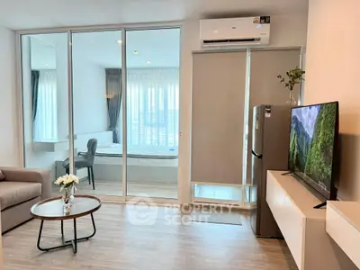 Modern apartment interior with open living room and bedroom, featuring sleek furniture and natural light.