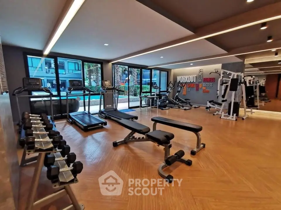 Modern gym with state-of-the-art equipment and large windows in a luxury residential complex.