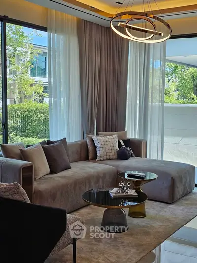 Luxurious living room with modern furniture and large windows offering a serene garden view.