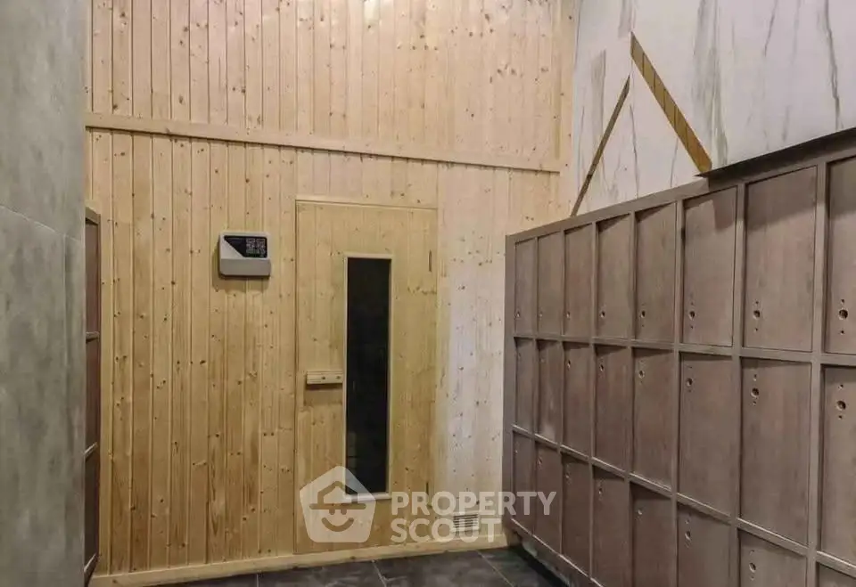 Modern sauna room with wooden paneling and lockers in a luxury building.