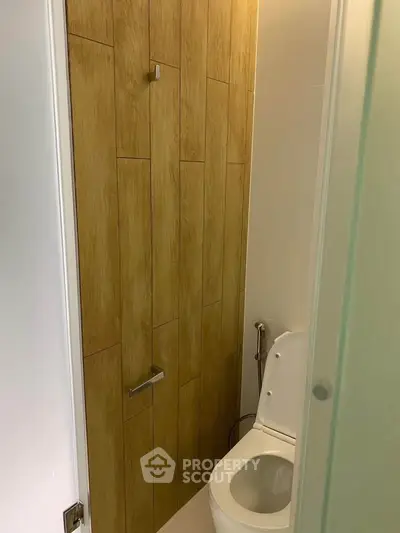 Modern bathroom with wooden accent wall and sleek toilet design.
