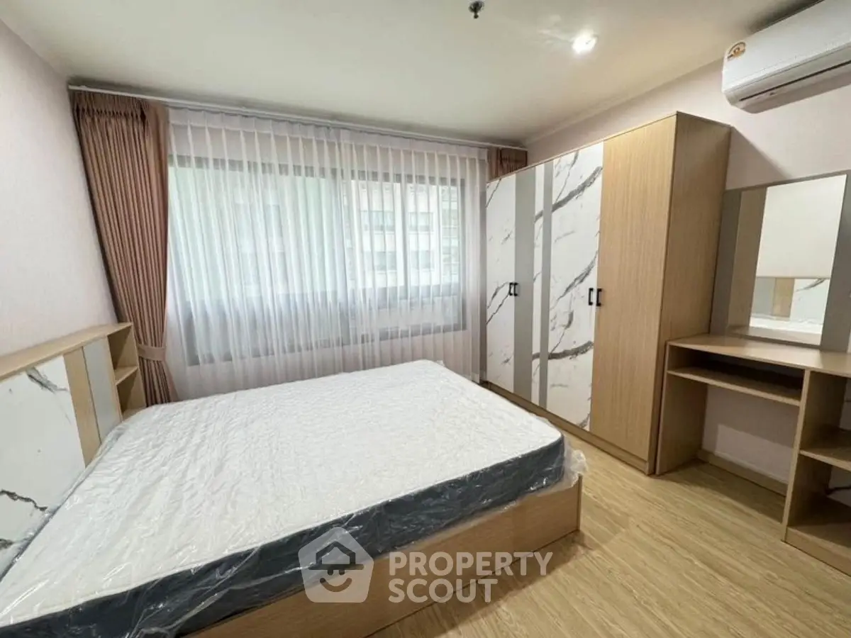 Spacious bedroom with modern furnishings and large window for natural light.