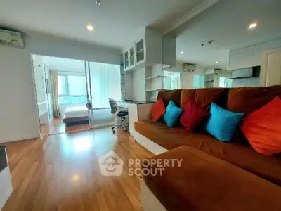 Spacious living room with modern decor and view into a cozy bedroom