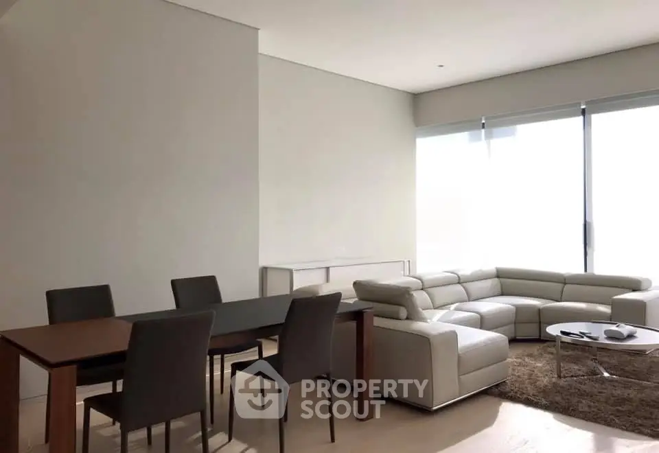 Modern living room with sleek furniture and large windows offering natural light.