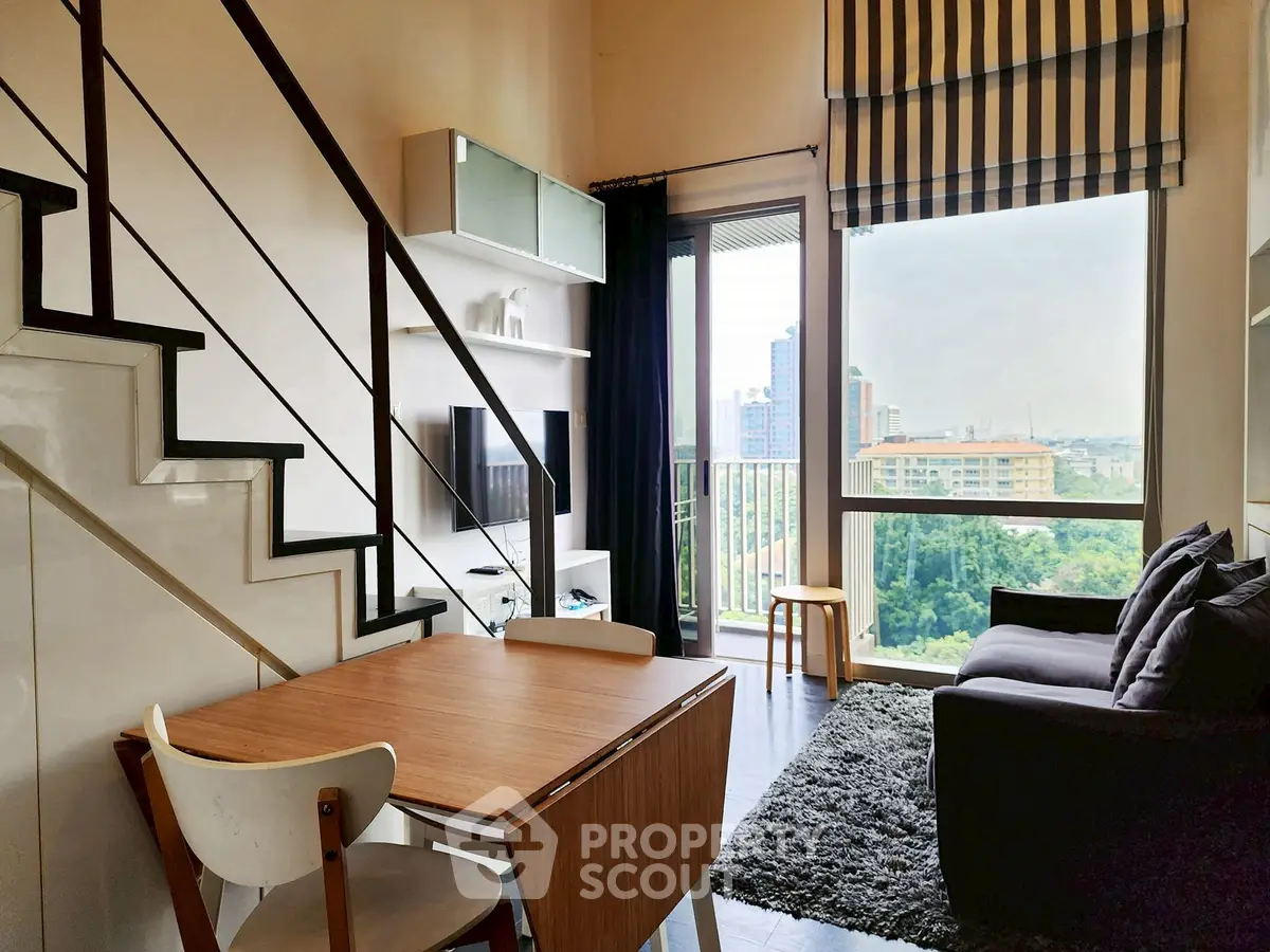 Modern living room with staircase, large window, and stylish decor in urban apartment.