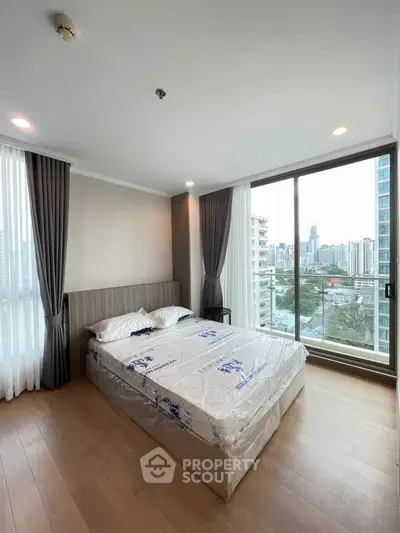 Modern bedroom with city view and large windows in a high-rise apartment.