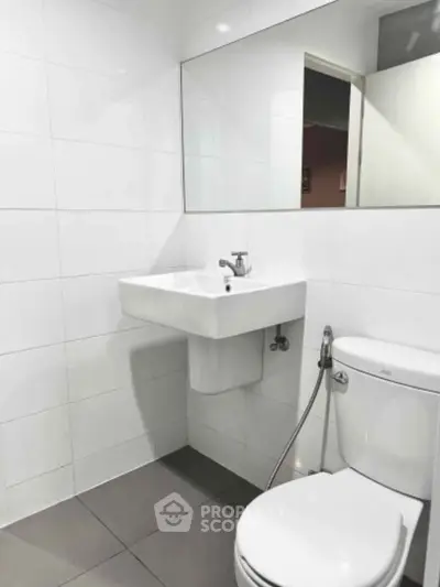 Modern minimalist bathroom with sleek white tiles and contemporary fixtures.