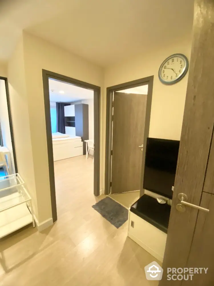 Modern apartment hallway leading to bedroom with stylish decor and wooden flooring.