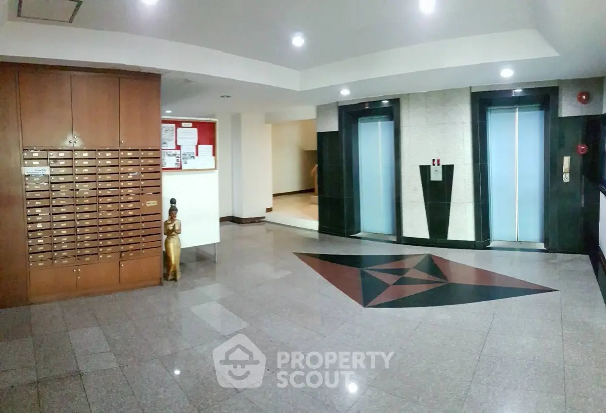 Spacious modern building lobby with elevators and mailboxes, featuring elegant flooring and ambient lighting.