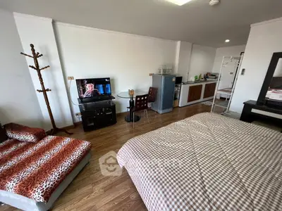 Spacious studio apartment with modern furnishings and open layout, featuring a cozy bed, TV, and kitchenette.