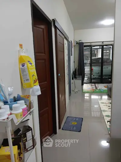 Cozy hallway leading to a bright living room with modern decor and glass doors.