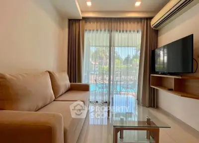 Modern living room with pool view, featuring a cozy sofa and wall-mounted TV, perfect for relaxation.