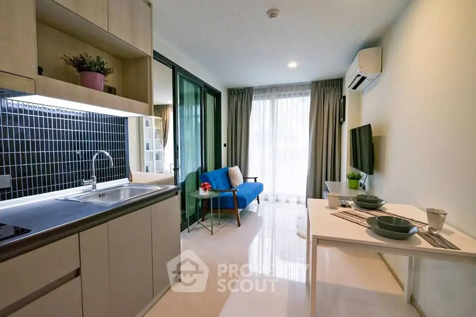 Modern open-layout living room with kitchen, featuring sleek design and natural light.