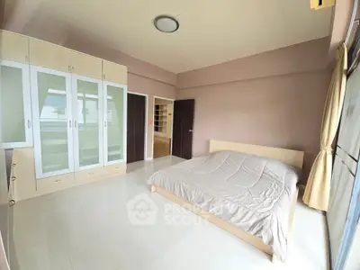Spacious bedroom with modern built-in wardrobe and large window for natural light.