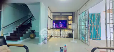 Spacious living room with modern decor and entertainment center, featuring sleek staircase and large windows.