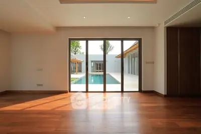 Spacious living room with wooden floors and pool view through large glass doors.