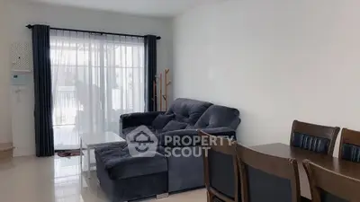 Spacious living room with plush sofa and dining area, featuring large windows for natural light.