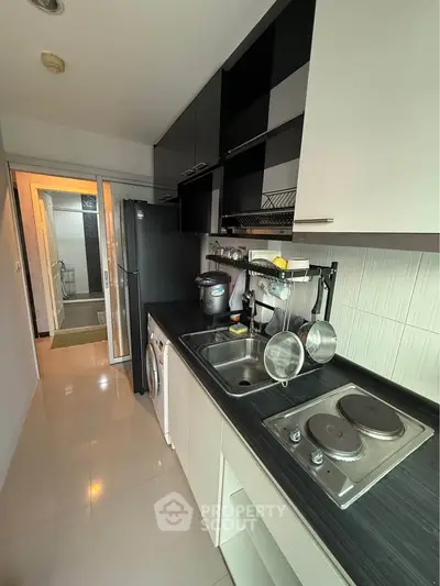Modern kitchen with sleek black and white design, featuring electric stove and ample storage space.