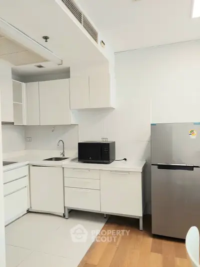 Modern kitchen with sleek white cabinets and stainless steel fridge