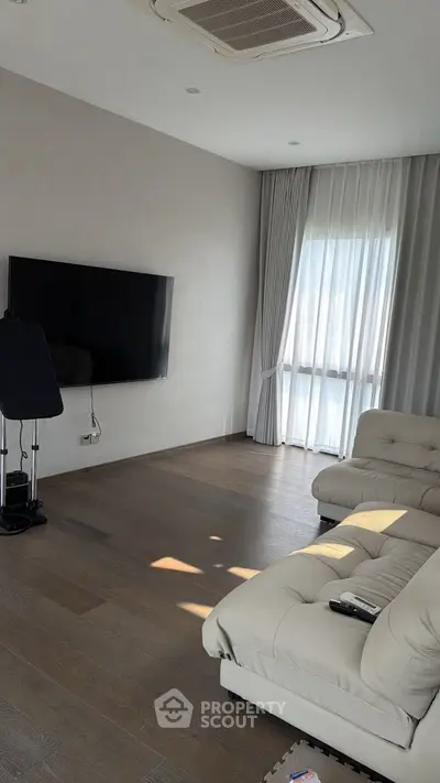 Spacious modern living room with elegant furniture and large window for natural light.