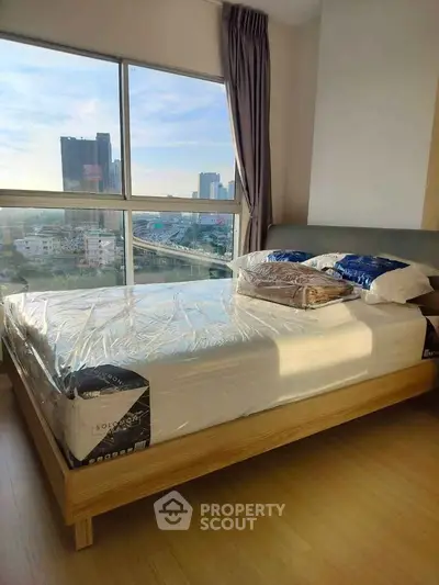 Modern bedroom with large window offering stunning city view, featuring a neatly made bed and wooden flooring.